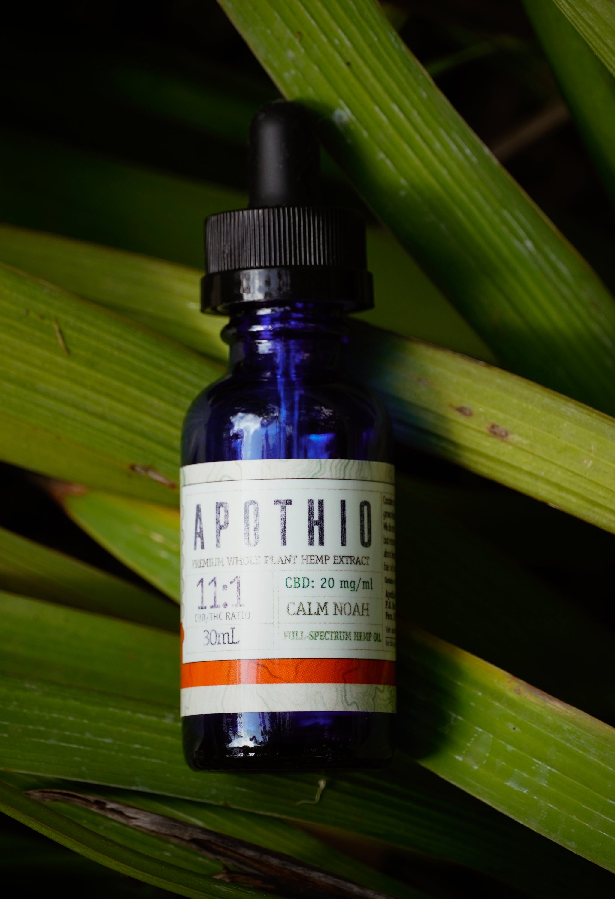 Blue bottle with dropper labeled 'Apothio' on green leaves
